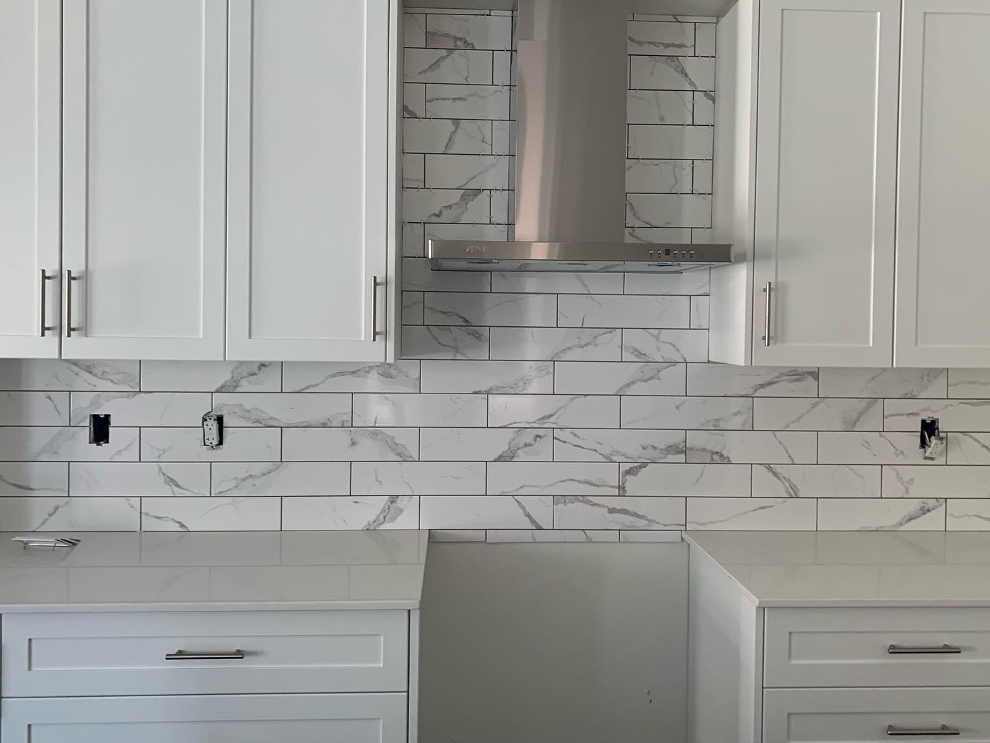 Detailed marble-look backsplash installation around a range hood